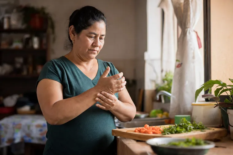Mujer peruana de unos 52 años se masajea la muñeca y los nudillos por rigidez en las manos